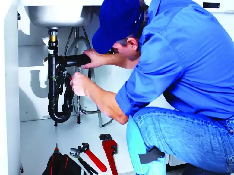 Picture of a plumbing contractor making repairs under a bathroom sink